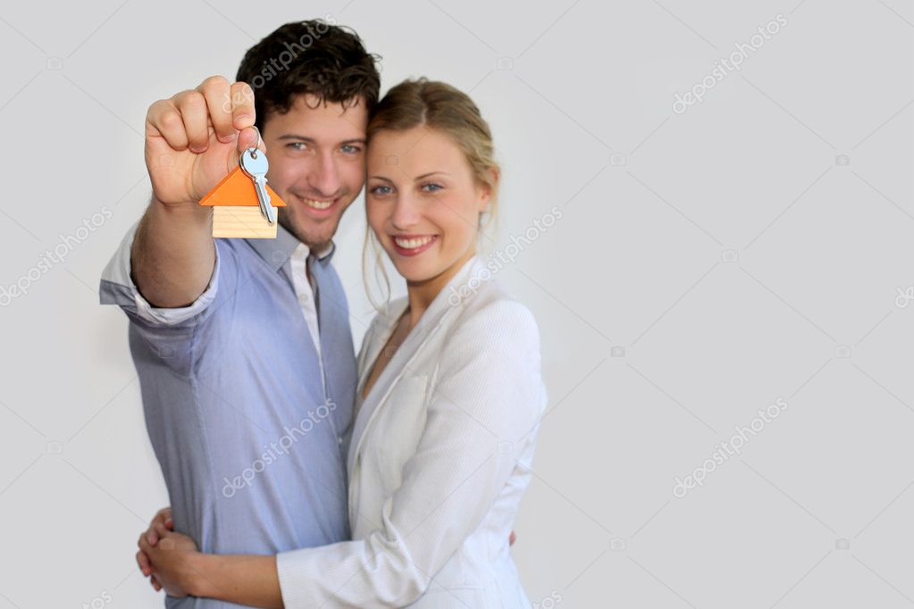 Young smiling couple holding keys of their new house