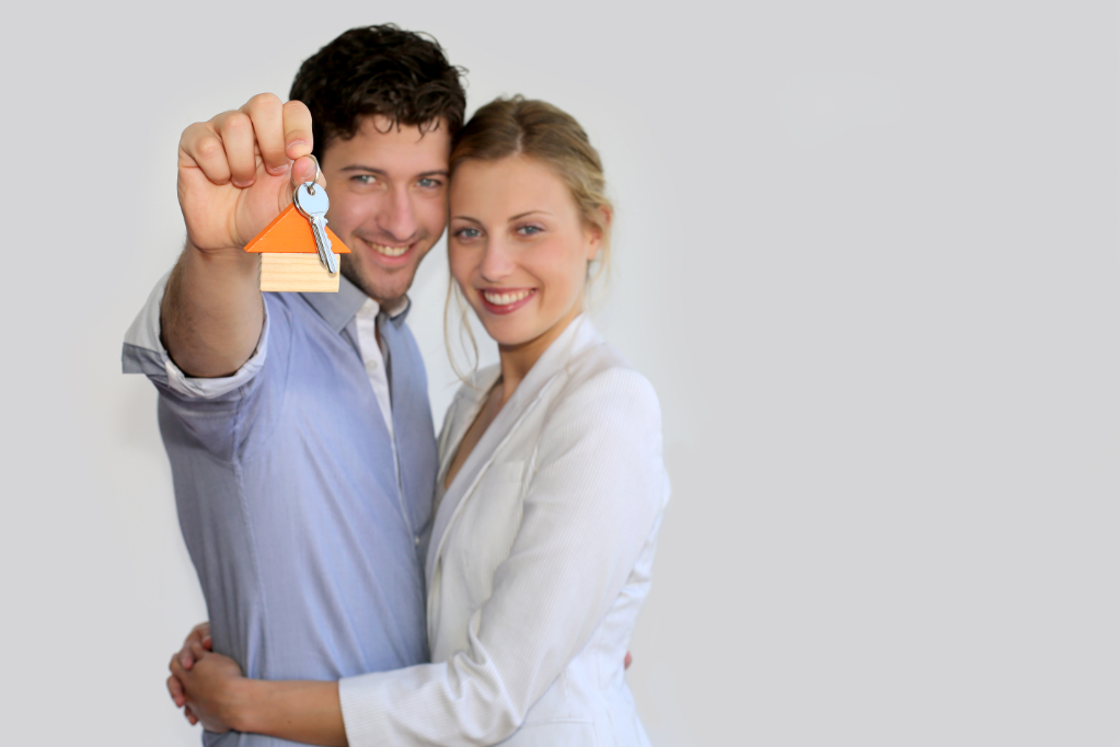 Young smiling couple holding keys of their new house